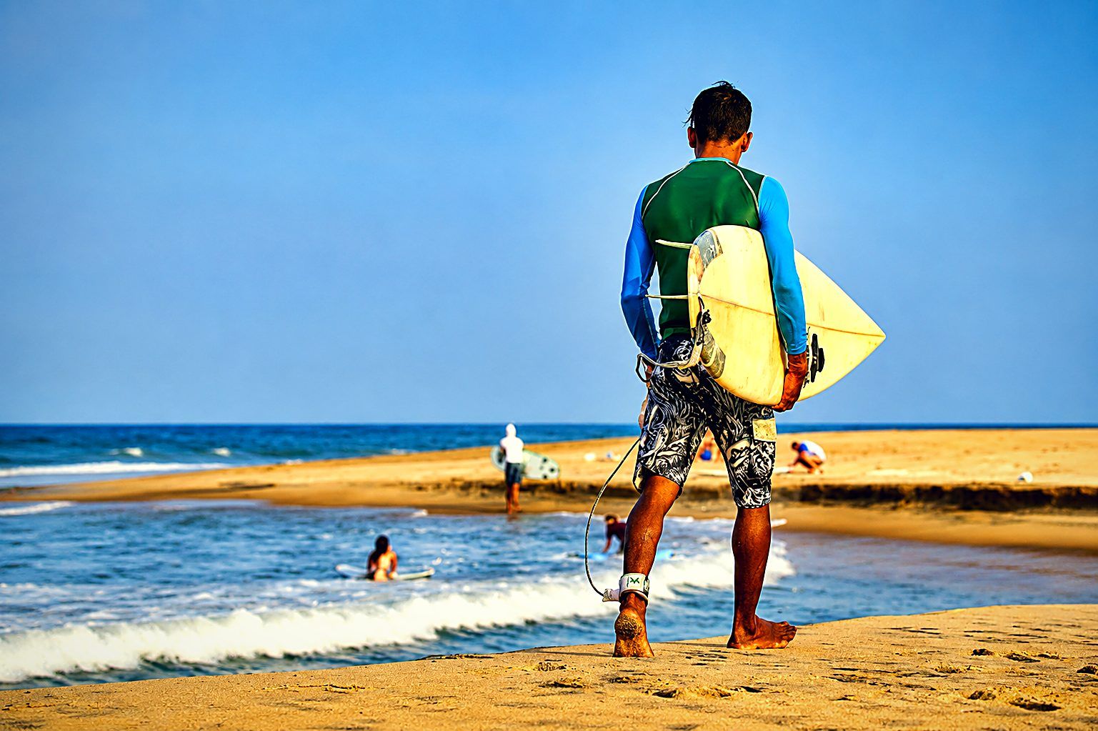 Surfer walking the beach with a board at Arugam Bay